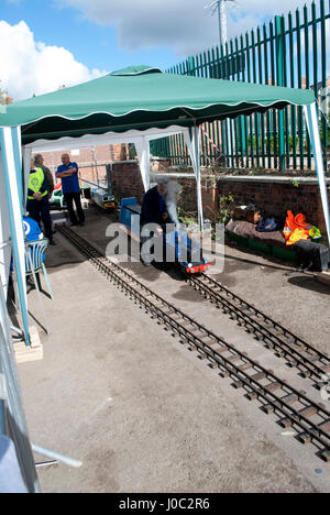 Mann sitzt auf Modell-Dampfeisenbahn Stockfoto