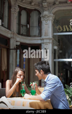 Junges Paar sitzt außerhalb Café, trinken Cocktails, Turin, Piemont, Italien Stockfoto