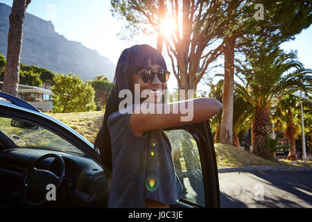 Porträt der jungen Frau neben dem Auto stand, stützte sich auf offene Autotür Stockfoto