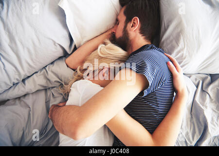 Paar zusammen im Bett liegen, schlafen, Arme umeinander Stockfoto