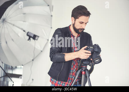 Männlichen Fotografen Überprüfung Studio Fotoshooting auf digitale slr Stockfoto