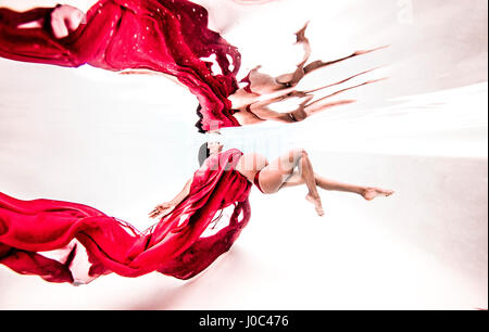 Unterwasser-Blick bereit junge schwangere Frau mit wehenden roten Textil Stockfoto