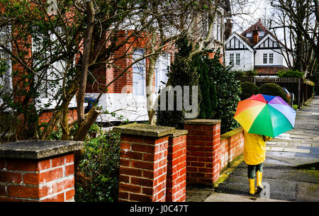Rückansicht des jungen in gelben Anorak mit Regenschirm Strasse Stockfoto
