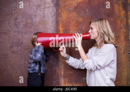 Frau in Megaphon, jungen hören, Kopf in Megaphon sprechen Stockfoto