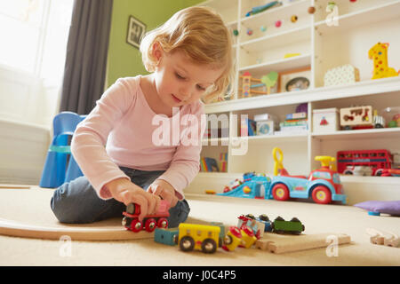 Weiblichen Kleinkind spielt mit Spielzeugeisenbahn im Spielzimmer Stock Stockfoto