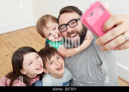 Mitte erwachsener Mann und drei Kinder unter Smartphone selfie Stockfoto