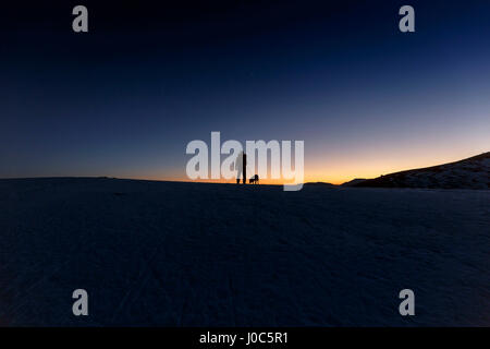 Silhouette Ansicht von Mensch und Hund stehen am Hügel Horizont in der Nacht Stockfoto