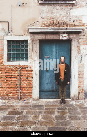 Porträt des bärtigen Mitte erwachsenen Mann stand vor der alten Tür, Venedig, Italien Stockfoto