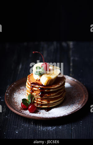 Amerikanische Pfannkuchen auf einem Teller mit Banane, Kirsche und Minze Stockfoto