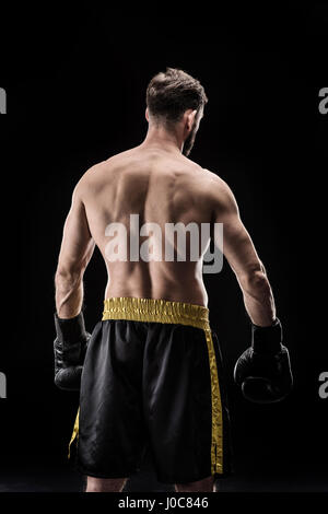 Rückansicht des jungen muskulösen Sportler in Boxhandschuhen posiert auf schwarz Stockfoto