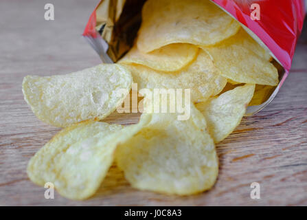 Geöffnete Tüte Kartoffelchips auf Holztischplatte Stockfoto