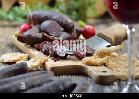 Südtiroler Marende mit typischen Wurstwaren ("Kaminwurzen") und knusprigen Fladenbrot (sogenannte Schuettelbrot), oft mit Wein aus der Region serviert Stockfoto