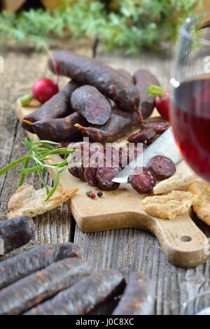 Südtiroler Marende mit typischen Wurstwaren ("Kaminwurzen") und knusprigen Fladenbrot (sogenannte Schuettelbrot), oft mit Wein aus der Region serviert Stockfoto