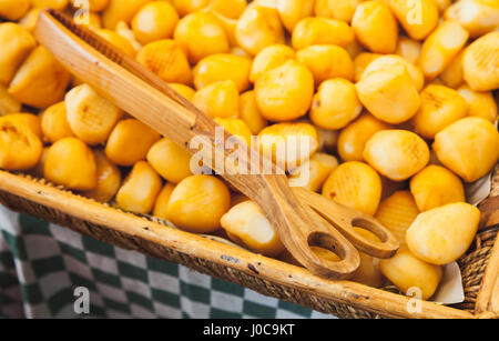 Kleine Köpfe von geräuchertem Käse mit einer hölzernen Zange lag in hölzernen Korb, Amsterdam Marktplatz Zähler Stockfoto