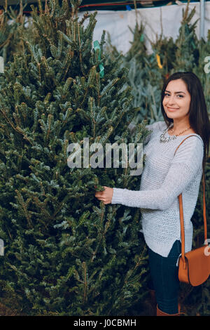 schönes Mädchen wählt einen Weihnachtsbaum auf der Messe Stockfoto