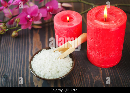 Meer-Badesalz, Kerzen und Blumen auf einem hölzernen Hintergrund. Das Konzept der Entspannung und Wellness. Stockfoto