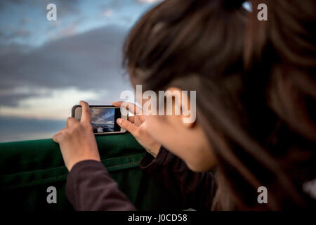 Junge Frau fotografieren Sonnenuntergang vom Boot an der Küste von Maine, USA Stockfoto