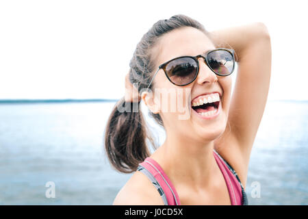 Junge Frau mit Sonnenbrille Lachen von Meer, Maine, USA Stockfoto