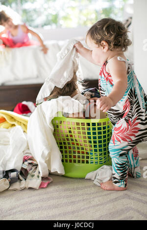 Weiblichen Kleinkind Kind versteckt im Wäschekorb Wäsche entfernen Stockfoto