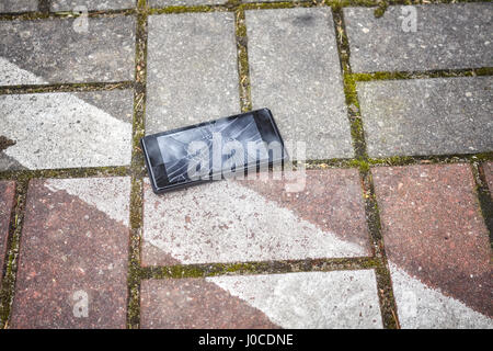 Nahaufnahme Bild eines Mobiltelefons mit gebrochenen Bildschirm auf dem Bürgersteig parken. Stockfoto