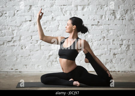 Attraktive Frau junge Yogi tun einem vierbeinigen King Pigeon pose Stockfoto