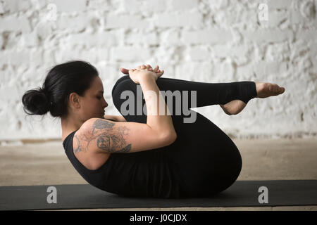 Attraktive Frau junge Yogi im Knie zur Brust darstellen, studio Stockfoto