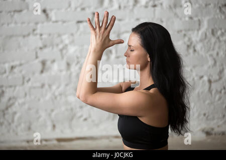 Junge Yogi attraktive Frau macht Namaste, weiße Loft Zeitmessung Stockfoto