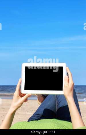 Bild von weiblichen Händen mit Tablet-Computer an einem Strand, schwarzer Bildschirm für textfreiraum hautnah. Stockfoto