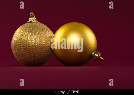 Nahaufnahme von goldenen Weihnachtskugeln auf rotem Grund Stockfoto