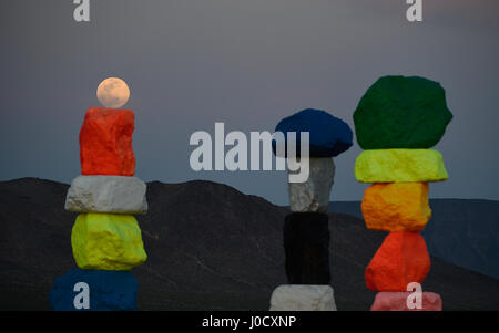 Jean, Nevada, USA. 10. April 2017. Ein Vollmond steigt über die große Kunst im öffentlichen Raum-Installation mit dem Titel sieben Magic Mountains des Schweizer Künstlers Ugo Rondinone 10. April 2017 in der Nähe von Jean, Nevada. Das Kunstwerk, bestehend aus sieben Türme der bunten, gestapelte Felsen stehend mehr als dreißig Fuß hoch, wird voraussichtlich bis Mai 2018 angezeigt werden. Bildnachweis: David Becker/ZUMA Draht/Alamy Live-Nachrichten Stockfoto