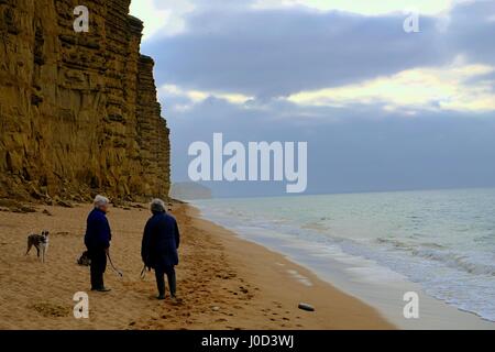 West Bay, Dorset, UK. 12. April 2017. Am frühen Morgen Hund Spaziergänger packen Sie sich Warm und dramatische Wolken über West Bay genießen, als am Morgen, die Temperatur an der Küste von Dorset. Bildnachweis: Tom Corban/Alamy Live-Nachrichten Stockfoto