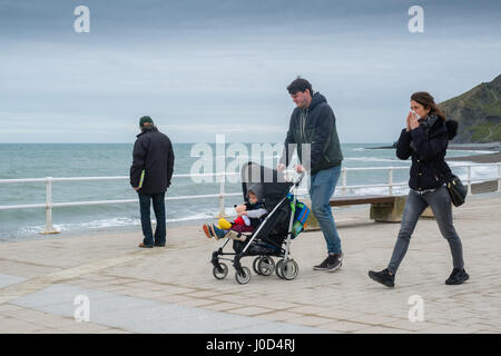 Aberystwyth Wales UK.  Mittwoch, 12. April 2017 UK Wetter: kalter, grau, windiger und bewölkter Tag in Aberystwyth, Wales, wie Familien Fuß entlang der Strandpromenade im Vorfeld bis Ostern Urlaubswochenende Foto Keith Morris / Alamy Live News Stockfoto