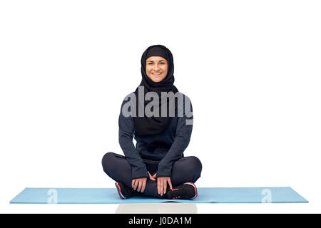 muslimische Frau tut Sport auf Matte Stockfoto