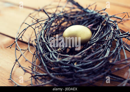 Nahaufnahme eines goldenen Osterei im Nest auf Holz Stockfoto