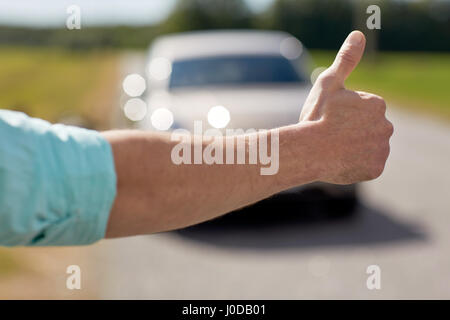 Mann, per Anhalter und Anhalten von Autos mit Daumen nach oben Stockfoto