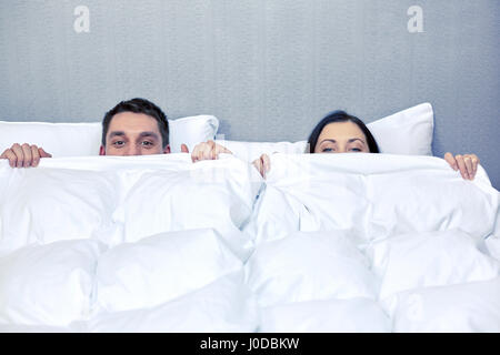 glückliches Paar versteckt unter der Decke im Bett Stockfoto