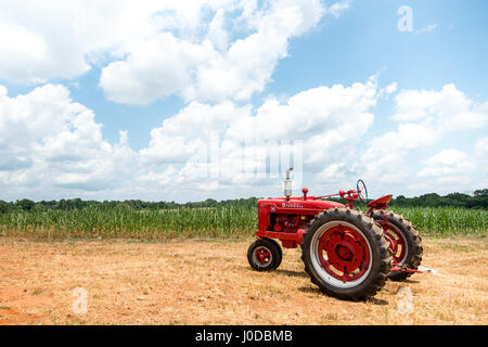 Ein roter McCormick Farmhall Traktor vor einem Feld in North Carolina während der Sommermonate. Stockfoto