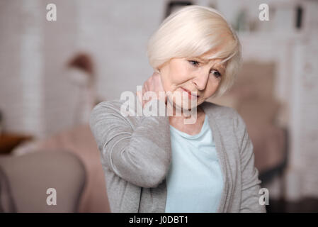 Fühle mich schlecht. Porträt von ziemlich ältere Dame ihren schmerzenden Hals berühren hautnah. Stockfoto