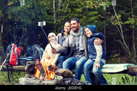 Familie mit Smartphone unter Selfie nahe am Lagerfeuer Stockfoto