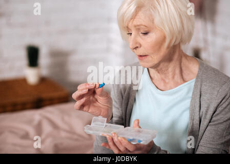 Meine kleine Hilfe. Seitenansicht des senior Lady hält Pille und aufmerksam betrachtet man es hautnah. Stockfoto