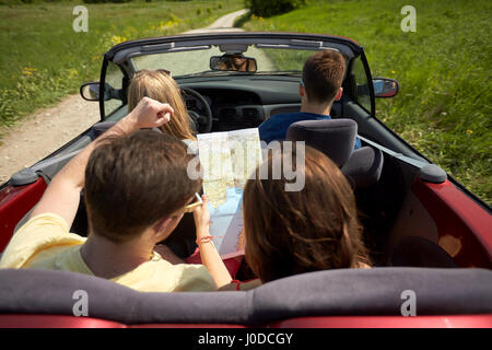 Glückliche Freunde mit Karte im Cabrio fahren Stockfoto