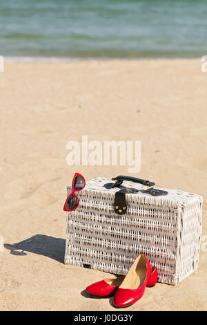 Sommer-Urlaub am Meer. Weiße Weide Koffer und Damen Accessoires und Schuhe am Strand. Selektiven Fokus. Stockfoto