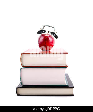 Ein roter Apfel mit Alarmglocken auf einem Stapel Bücher isoliert auf weißem Hintergrund. Zeit, zur Schule, Konzept des Lernens, Lehre, Alphabetisierung zurückzukehren. Stockfoto