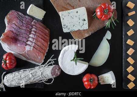 Mischung von italienischen und französischen Käse und Salami auf schwarzem Hintergrund, lag flach. Stockfoto