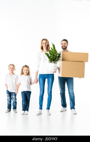 Glückliche Familie mit Kartons und Grünpflanze Umzug in neues Haus Stockfoto