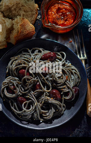 Schwarze Nudeln mit Oliven und rotem pesto Stockfoto