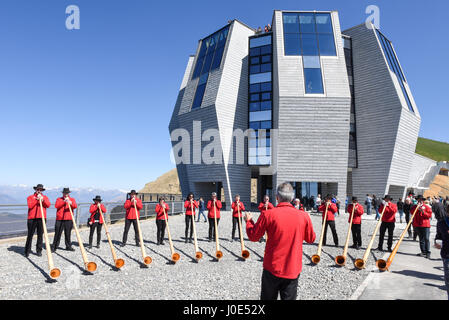 Monte Generoso, Schweiz - 8. April 2017: Menschen, die spielen des Alphorns vor dem modernen Restaurant am Monte Generoso auf die Schweizer Alpen Stockfoto