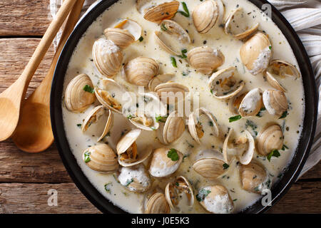 Leckere Muscheln in einer cremigen Sauce mit Knoblauch und grünen Nahaufnahme auf einem Teller auf den Tisch. horizontale Ansicht von oben Stockfoto