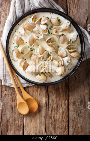 Delikatessen Essen: Muscheln gedünstet in Creme mit Knoblauch und grünen Nahaufnahme auf einem Teller auf den Tisch. Vertikale Ansicht von oben Stockfoto