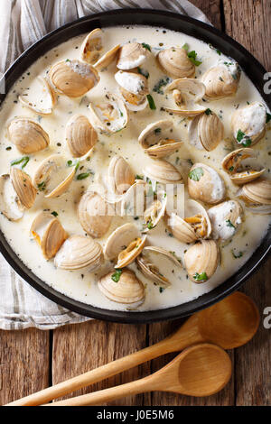 Leckere Muscheln in einer cremigen Sauce mit Knoblauch und grünen Nahaufnahme auf einem Teller auf den Tisch. Vertikale Ansicht von oben Stockfoto